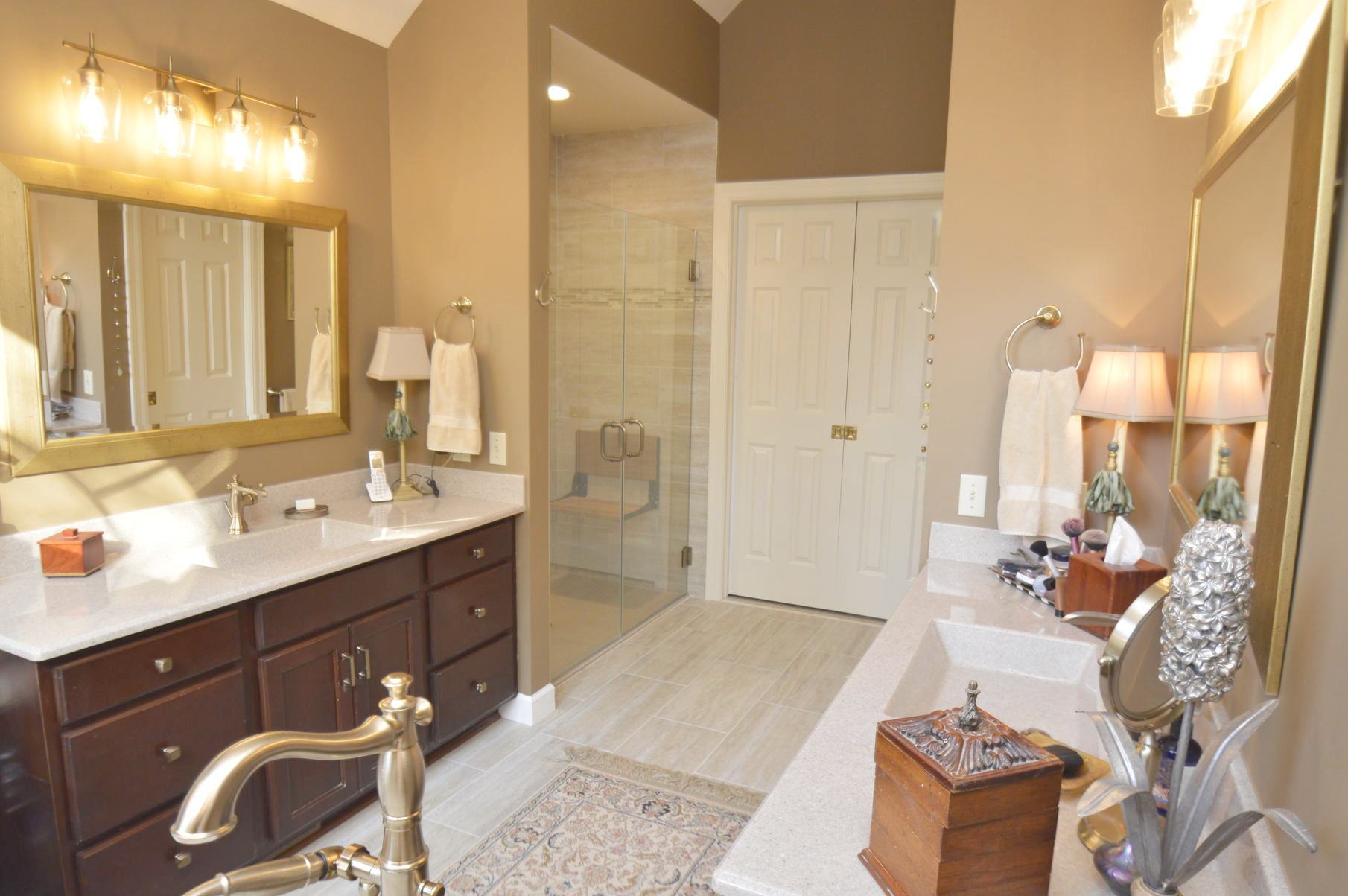 A remodeled bathroom with marble countertops, a large mirror in front of the sink and a walk in shower