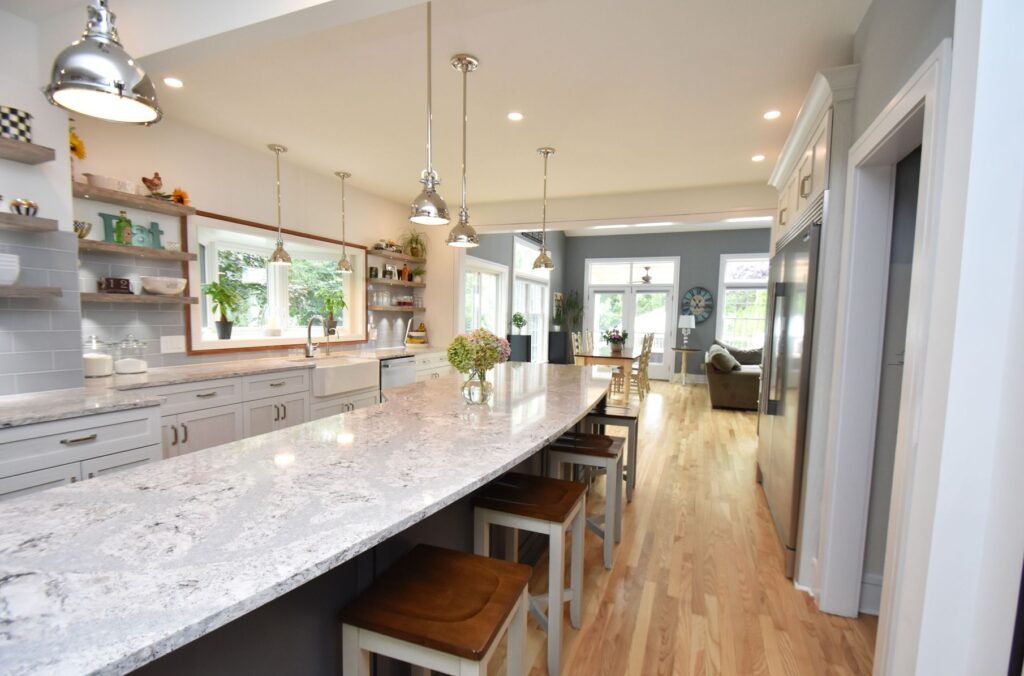 kitchen and bath renovation - A kitchen remodeled with grey backsplash and a long granite countertop island
