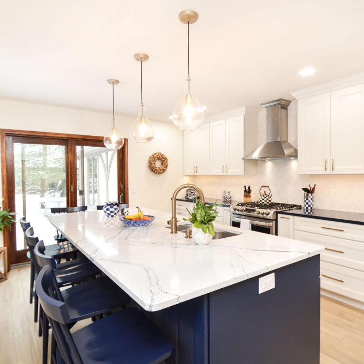 DSC_8641-2 A remodeled kitchen with marble countertops and white cabinets. There's a fruit bowl, plant, and decorative vase on the counter