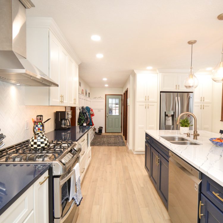DSC_8673-2 A remodeled kitchen with marble countertops and white cabinets. There's a fruit bowl, plant, and decorative vase on the counter