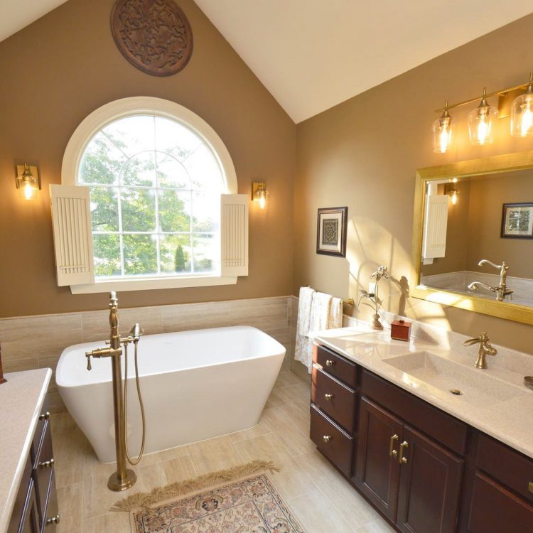 Fairway (6) A remodeled bathroom with marble countertops, a large mirror in front of the sink and a standalone tub in front of an arched window