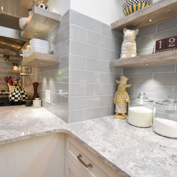 Five mile line road (22) A remodeled kitchen highlighting the marble countertops and grey subway tile backsplash. There is an assortment of trinkets and jars on the counter